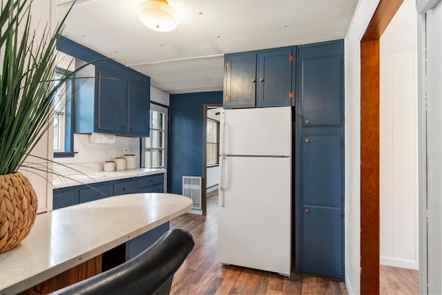 kitchen with blue cabinetry, dark wood-type flooring, and white fridge