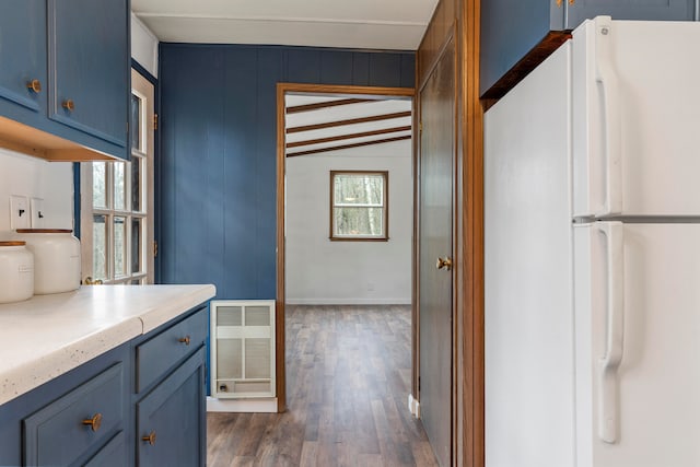 kitchen featuring blue cabinetry, plenty of natural light, white fridge, and lofted ceiling