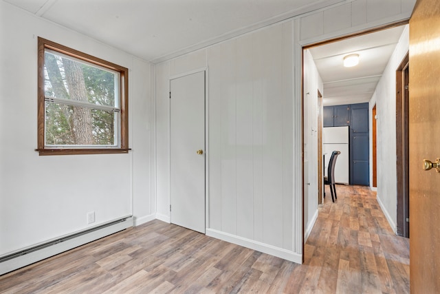 unfurnished bedroom featuring baseboard heating, hardwood / wood-style flooring, and white refrigerator