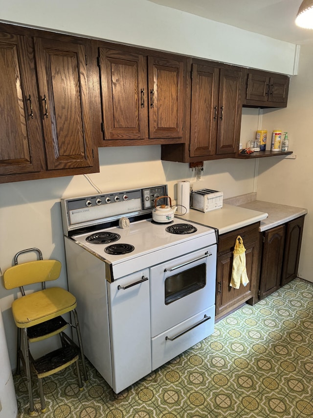 kitchen featuring dark brown cabinetry, white range with electric stovetop, and light tile patterned floors