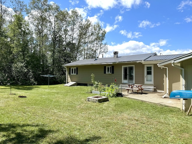 rear view of house with metal roof, a yard, and a patio area