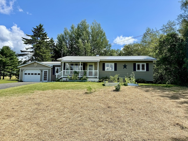 single story home with an outbuilding, a front lawn, covered porch, and a garage