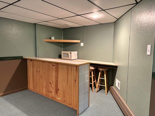 bar featuring a paneled ceiling, white microwave, and a baseboard radiator