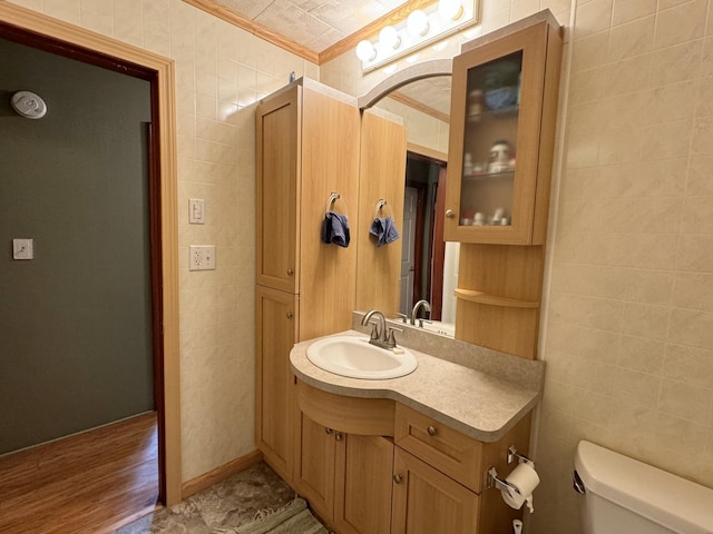 bathroom featuring toilet, ornamental molding, tile walls, and vanity