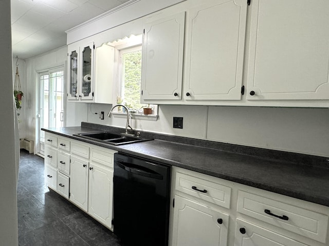 kitchen featuring black dishwasher, dark countertops, a sink, and white cabinets