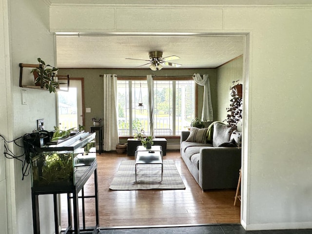 living area with ceiling fan, a textured ceiling, and wood finished floors