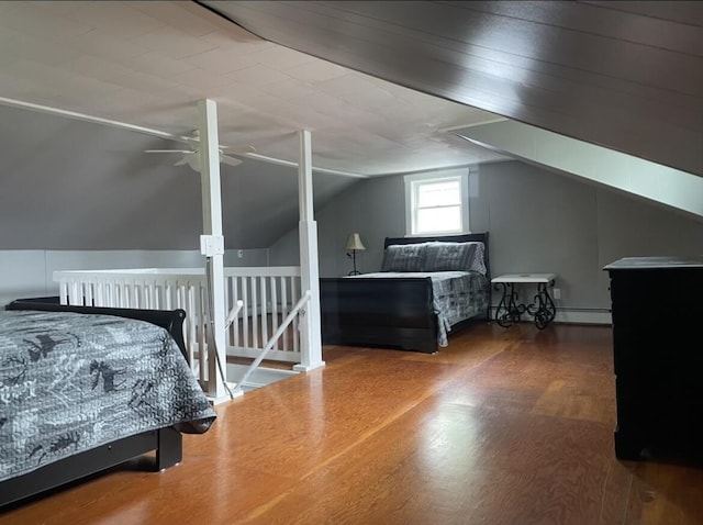 bedroom with a baseboard heating unit, lofted ceiling, and wood finished floors