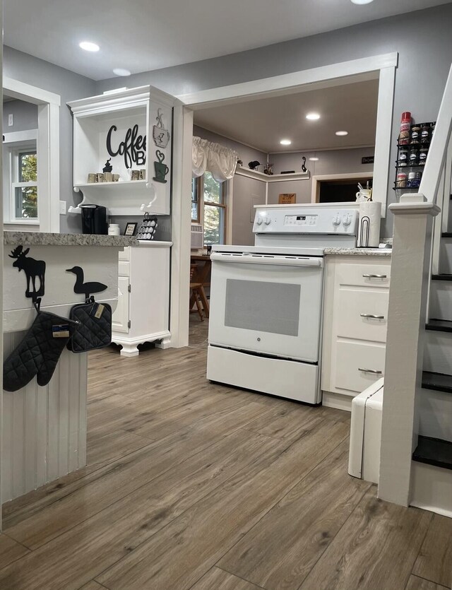 kitchen featuring electric stove, white cabinetry, open shelves, and wood finished floors