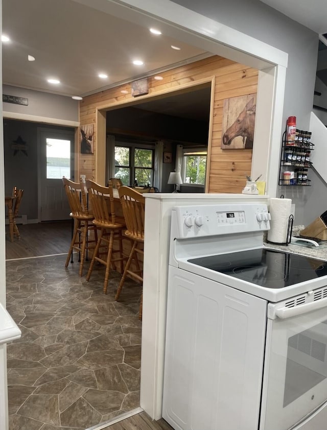 clothes washing area with laundry area, plenty of natural light, wooden walls, and recessed lighting