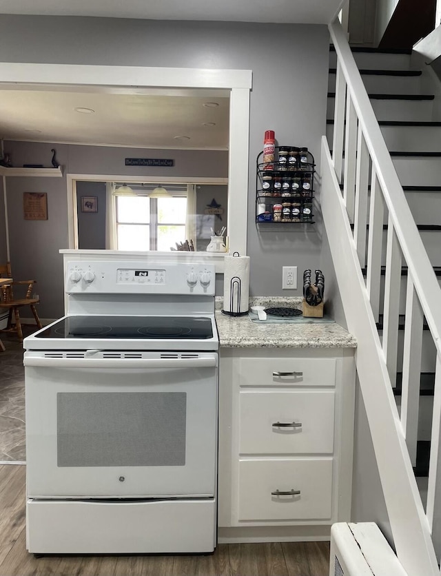 kitchen featuring white electric range, dark wood-type flooring, white cabinetry, and light stone counters