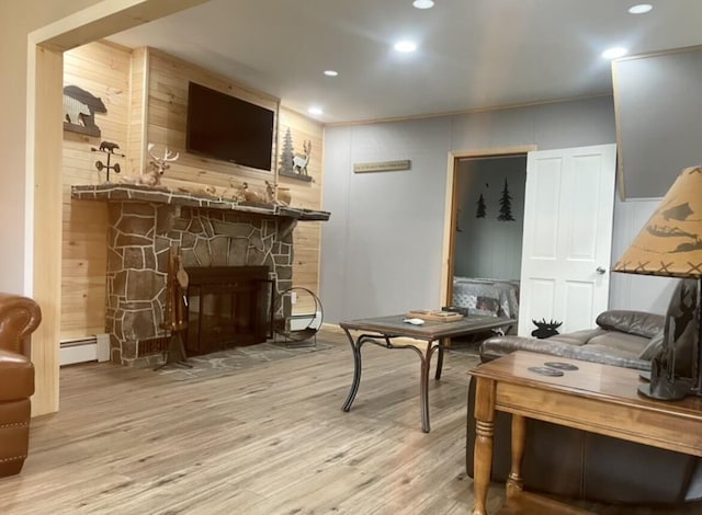 interior space featuring a stone fireplace, a baseboard radiator, wood finished floors, and recessed lighting