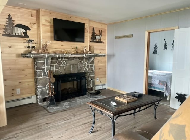 living room featuring a fireplace, a baseboard radiator, wood finished floors, and wooden walls