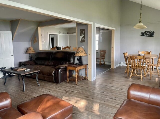 living area with baseboards, vaulted ceiling, baseboard heating, and wood finished floors