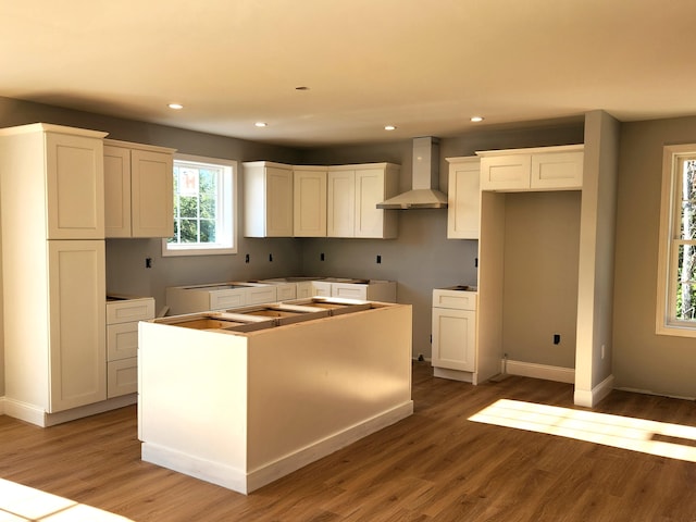 kitchen featuring hardwood / wood-style flooring, a center island, white cabinets, and wall chimney exhaust hood