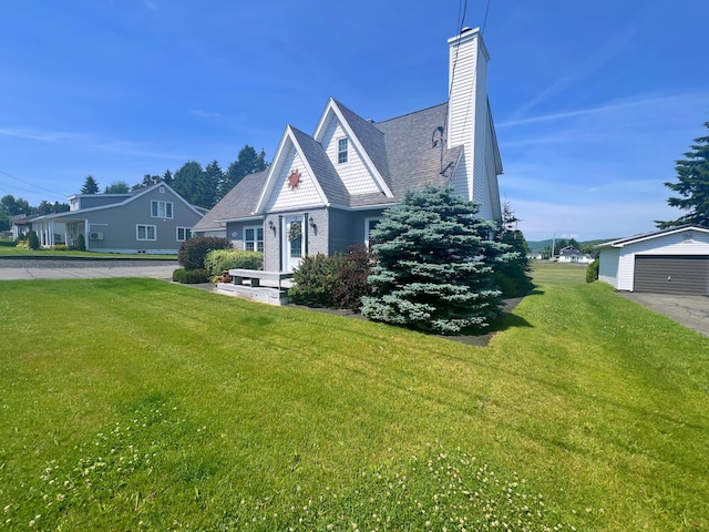 view of front facade featuring a front lawn, a garage, and an outdoor structure