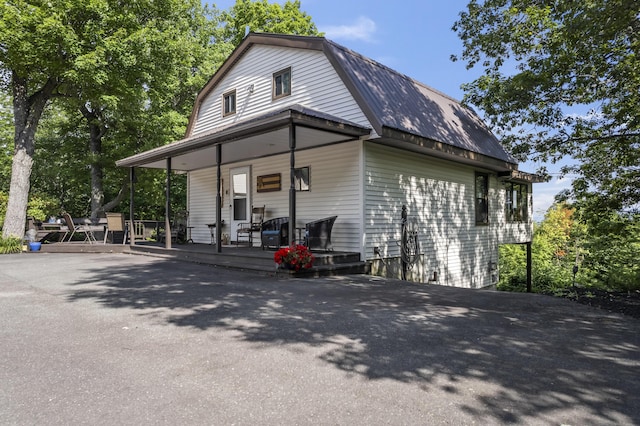 view of property exterior featuring a porch, metal roof, and a gambrel roof