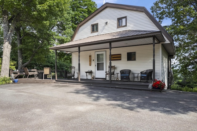 colonial inspired home featuring covered porch, metal roof, and a gambrel roof