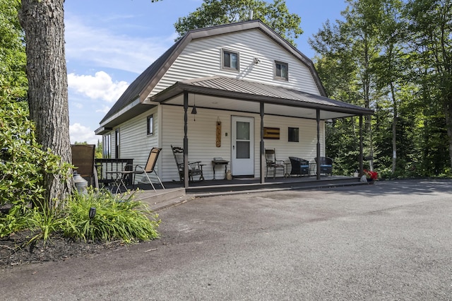 colonial inspired home featuring covered porch, metal roof, and a gambrel roof