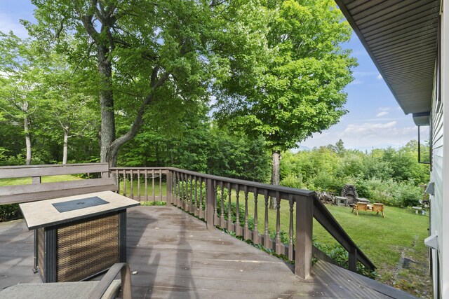 wooden terrace featuring a yard and a fire pit