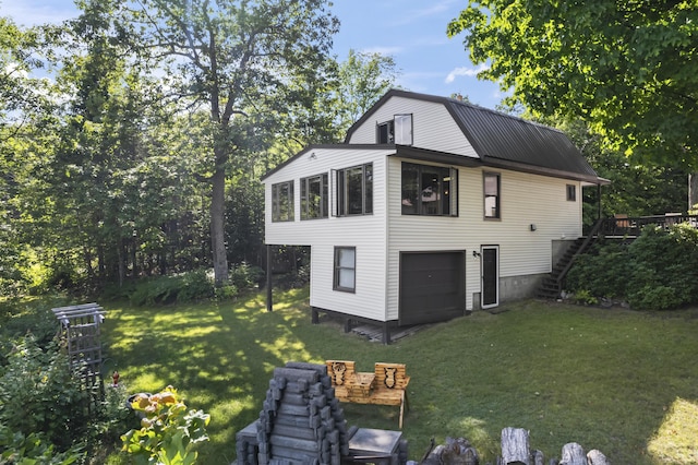 view of property exterior with a garage, a gambrel roof, stairway, metal roof, and a yard