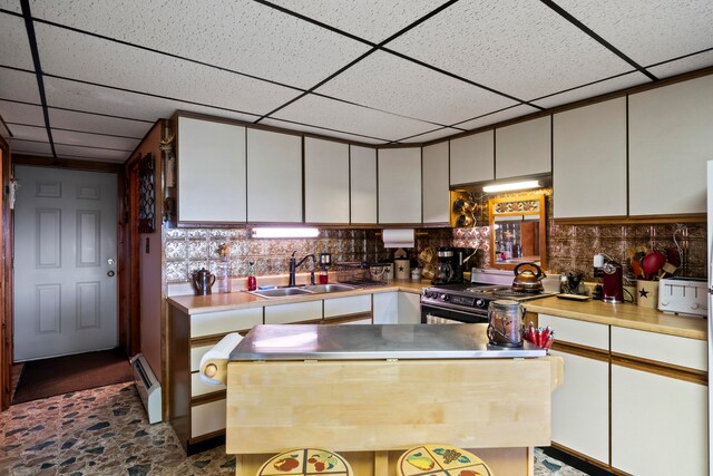 kitchen with a paneled ceiling, white cabinetry, high end stainless steel range, and sink