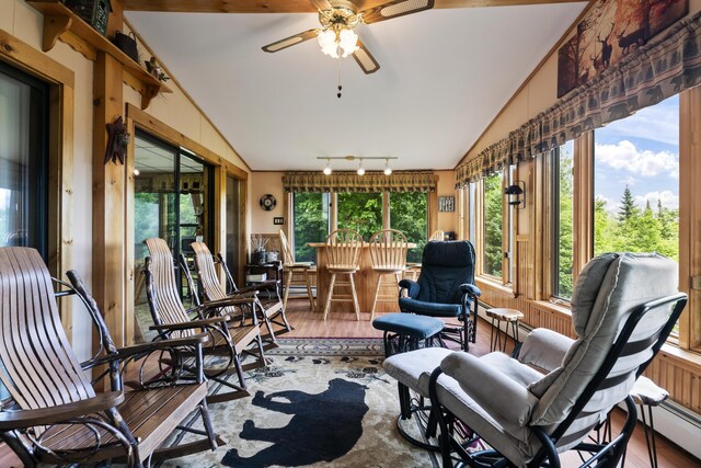 sunroom with a baseboard heating unit, rail lighting, ceiling fan, and lofted ceiling