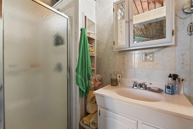 bathroom with tasteful backsplash, tile walls, vanity, and an enclosed shower