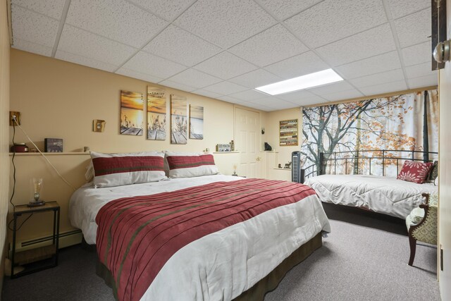 carpeted bedroom featuring baseboard heating and a drop ceiling