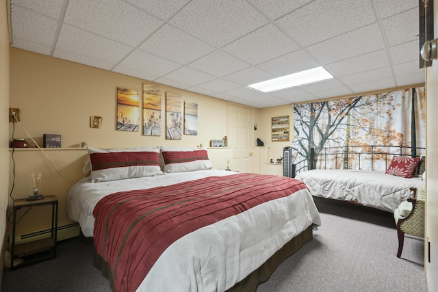 carpeted bedroom featuring a drop ceiling and baseboard heating