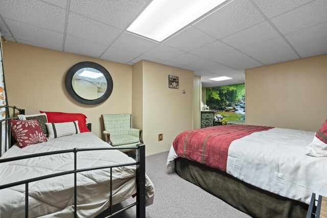 carpeted bedroom featuring a drop ceiling