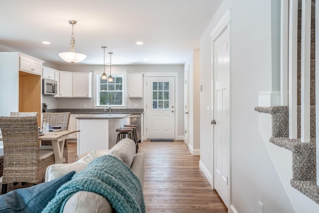 kitchen featuring hardwood / wood-style flooring, white cabinets, hanging light fixtures, and kitchen peninsula