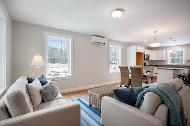 living room with light hardwood / wood-style flooring, an AC wall unit, and plenty of natural light