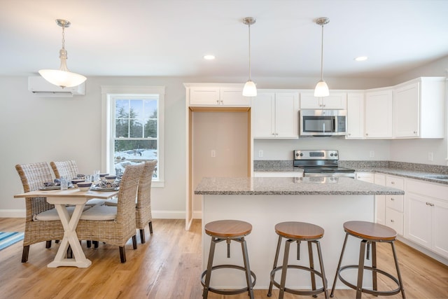 kitchen with light hardwood / wood-style flooring, pendant lighting, white cabinetry, light stone countertops, and stove