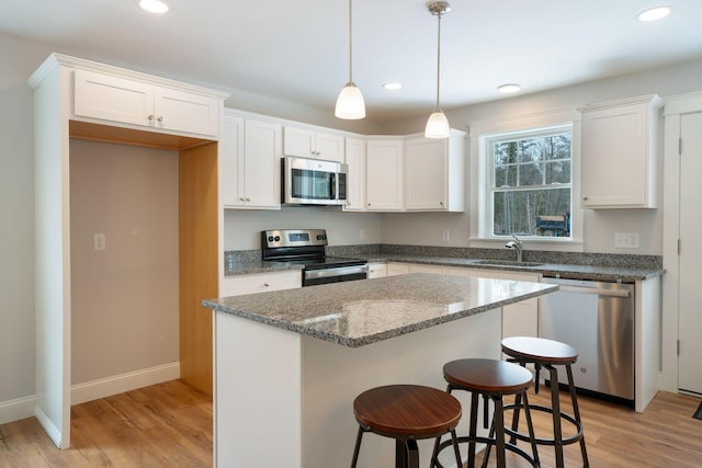 kitchen with sink, stainless steel appliances, white cabinetry, and light hardwood / wood-style flooring