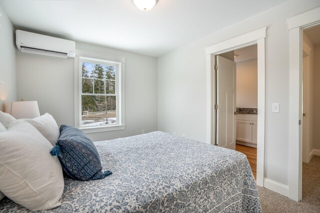 carpeted bedroom with an AC wall unit and ensuite bathroom