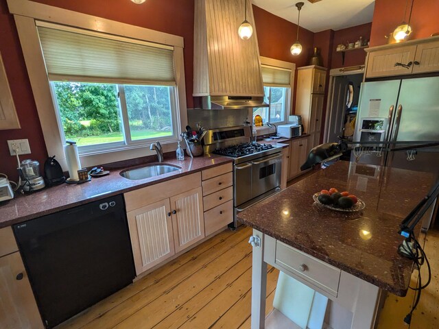 kitchen with sink, appliances with stainless steel finishes, light hardwood / wood-style floors, tasteful backsplash, and hanging light fixtures