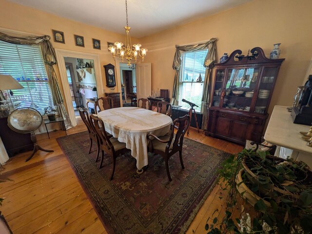 dining space featuring hardwood / wood-style floors and an inviting chandelier