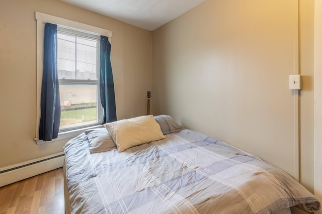 bedroom with light hardwood / wood-style flooring and baseboard heating