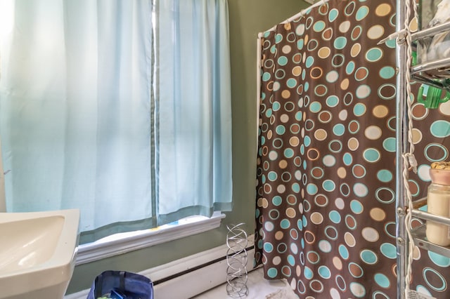 bathroom with sink, baseboard heating, and a shower with curtain