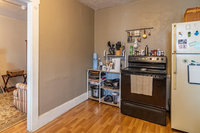 kitchen featuring light hardwood / wood-style flooring, range with electric cooktop, and white fridge