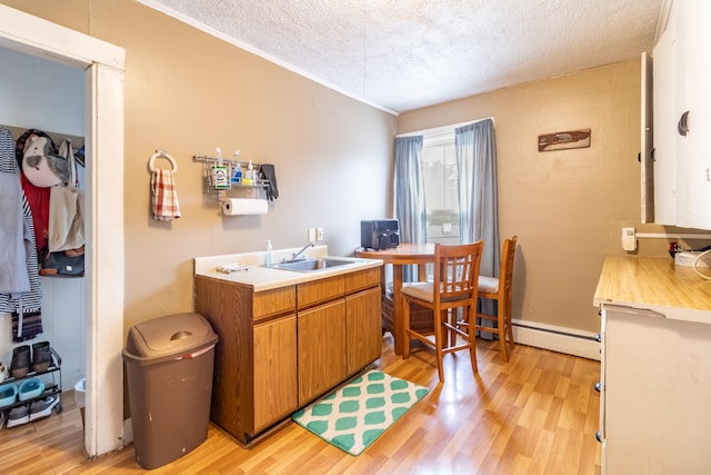 kitchen with light hardwood / wood-style floors, sink, a baseboard radiator, and a textured ceiling