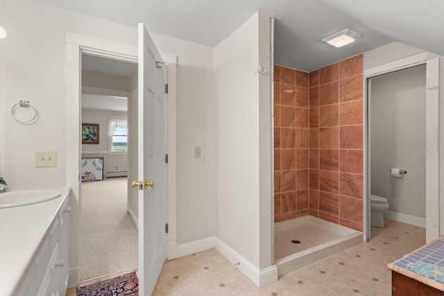 bathroom featuring baseboard heating, vanity, tiled shower, and toilet