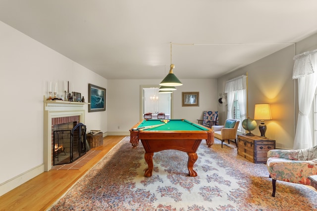 recreation room featuring hardwood / wood-style floors, billiards, and a brick fireplace