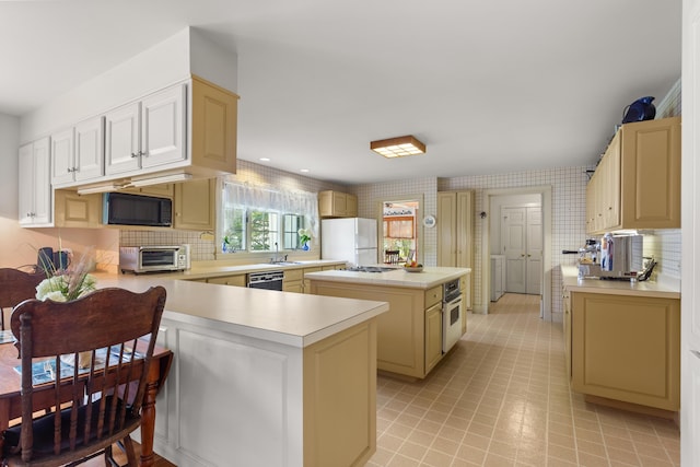 kitchen featuring sink, a center island, black appliances, kitchen peninsula, and tasteful backsplash