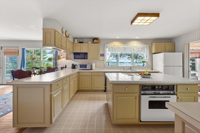 kitchen featuring white appliances, sink, a kitchen island, tile counters, and tasteful backsplash