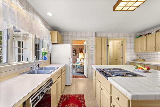 kitchen featuring stainless steel gas cooktop, black dishwasher, white refrigerator, sink, and light tile patterned floors