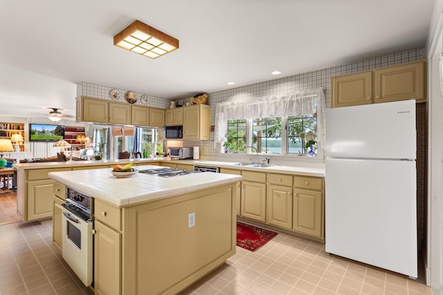 kitchen featuring tile countertops, kitchen peninsula, a center island, sink, and white appliances