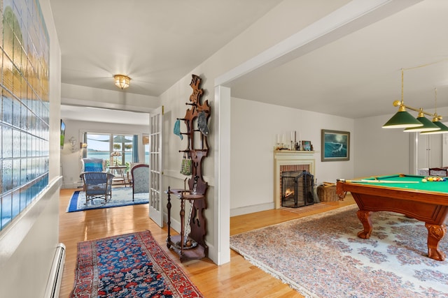 playroom with french doors, a brick fireplace, pool table, light hardwood / wood-style floors, and a baseboard heating unit