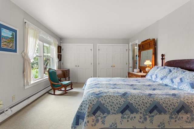 carpeted bedroom with a baseboard heating unit and two closets