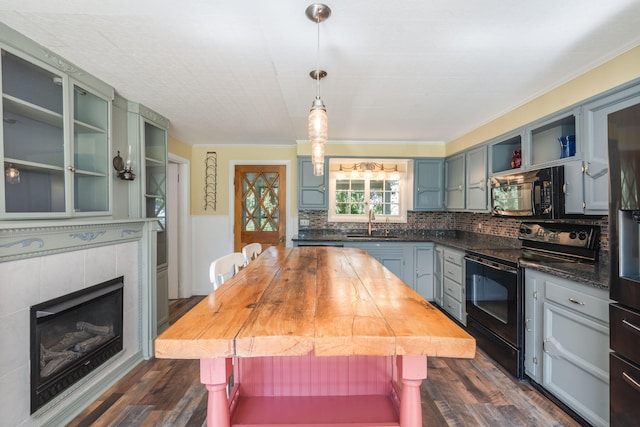 kitchen with tasteful backsplash, black appliances, dark hardwood / wood-style floors, and a tile fireplace